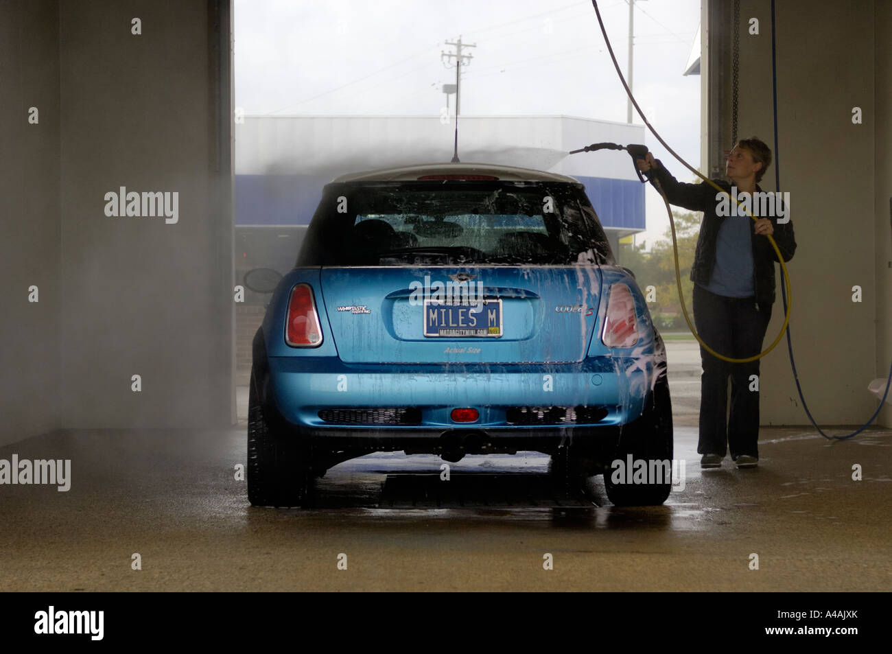 Woman washing a MINI Cooper S at a do it yourself car wash ...